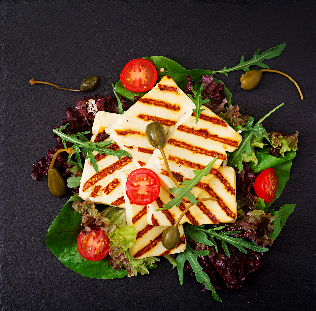 Fresh salad with grilled cheese, tomatoes, capers, lettuce and a